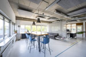 Modern ingerichte kantoorruimte aan de Anthony Fokkerweg met een hoge tafel, blauwe barkrukken en een zithoek.